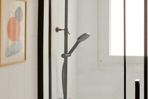 A bathroom with a shower, a framed abstract painting, and a window. - 165A By R2R - 2-Bedroom Apartment (Gijón)