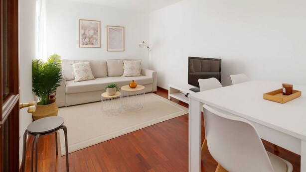 Uma sala de estar moderna com sofá, mesa de centro, televisão e área de jantar.
