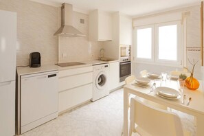 A modern kitchen with a dishwasher, washing machine, and oven. - 165A By R2R - 2-Bedroom Apartment (Gijón)