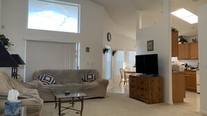 A living room with a sofa, coffee table, TV, and kitchen area.