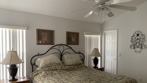 A bedroom with a bed, two bedside tables, a ceiling fan, and two wall-mounted lamps.