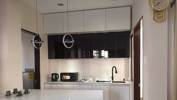 A modern kitchen with white cabinetry, a built-in oven, a microwave, a coffee maker, and a sink. - Elegant/ Centrally located townhouse. (Lapu-Lapu City)