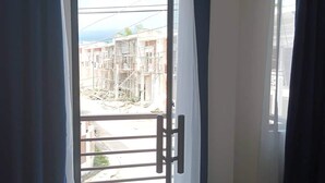 A bedroom with a bed, a balcony door, and a view of a building under construction. - Elegant/ Centrally located townhouse. (Lapu-Lapu City)