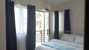 A bedroom with a bed, white bedding, and dark curtains. - Elegant/ Centrally located townhouse. (Lapu-Lapu City)