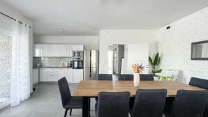 A modern kitchen with white cabinets, a wooden dining table, and black chairs.