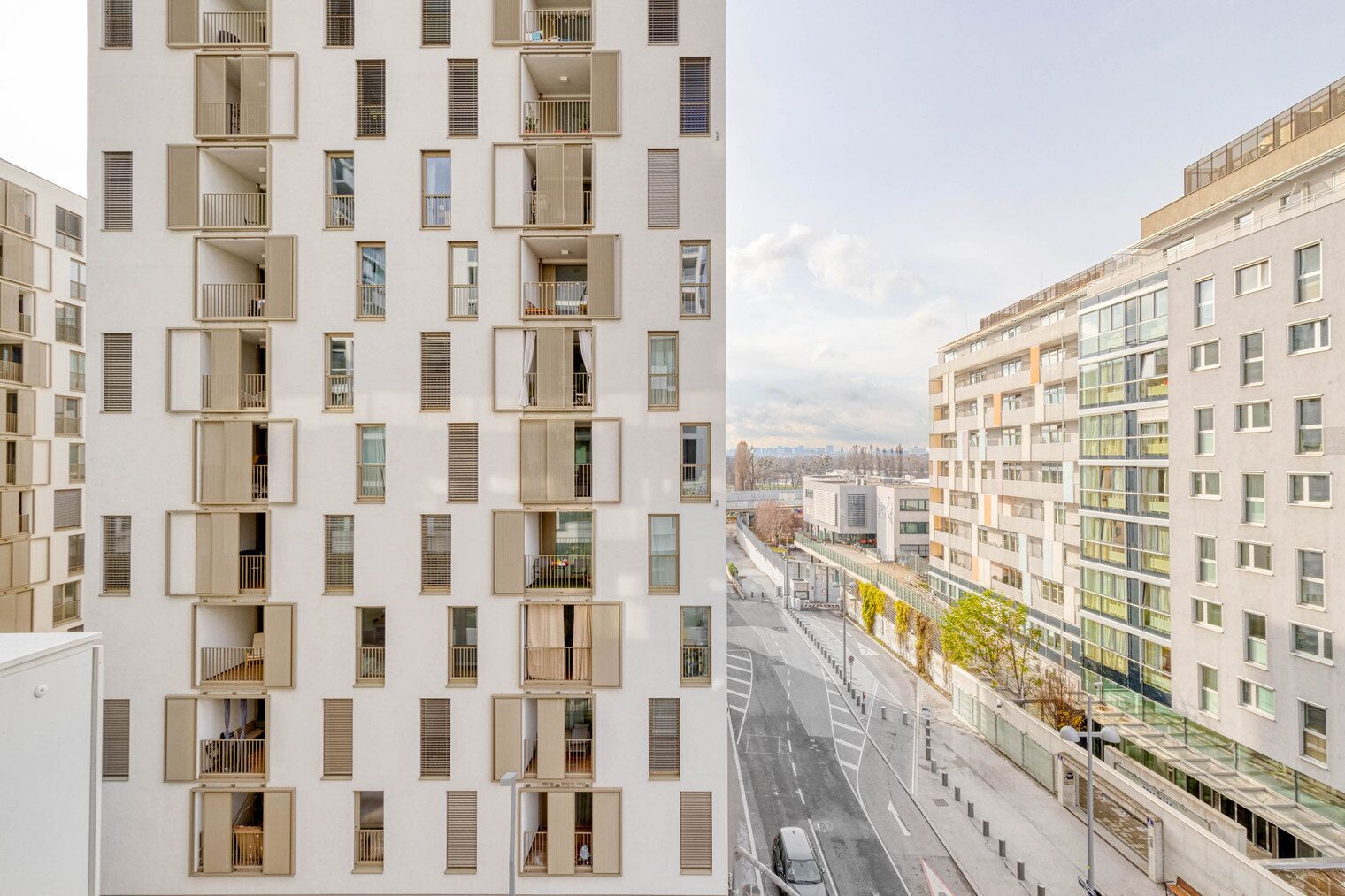A modern high-rise building with multiple balconies and a view of a cityscape.
