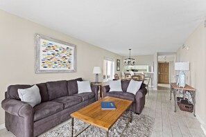 A living room with a brown leather sofa, a wooden coffee table, and a colorful abstract painting on the wall.
