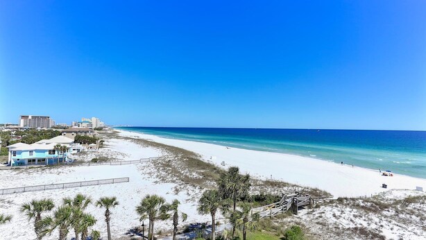 A beach with a clear view of the ocean, a sandy shoreline, and a few buildings in the background. - Destin on the Gulf 604- Stunning Gulf Views-Pool (Destin)