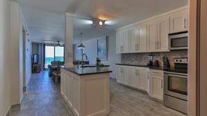 A modern kitchen with white cabinets, a central island, and stainless steel appliances. - Destin on the Gulf 604- Stunning Gulf Views-Pool (Destin)