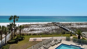 A beach resort with a pool, lounge chairs, and a wooden walkway leading to the beach. - Destin on the Gulf 606 (Destin)