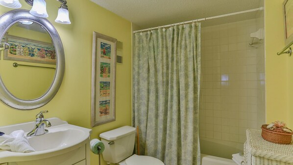 A bathroom with a sink, toilet, and shower curtain.