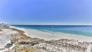A beach with a wooden boardwalk, sandy shore, and clear blue water. - Destin on the Gulf 706- Stunning Gulf Views-Pool (Destin)