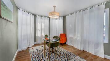 A room with a glass table, a chair, a rug, and a lamp.