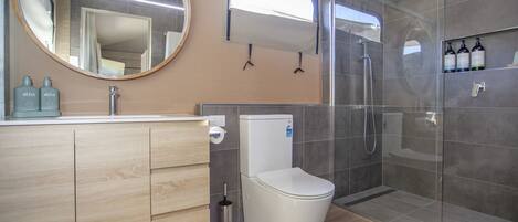 A modern bathroom with a toilet, sink, and shower.