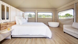 Un dormitorio moderno con una cama grande, una bañera y un sofá.