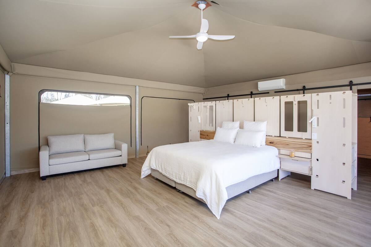 Ein Schlafzimmer mit einem Bett, einem weißen Sofa, einem Kleiderschrank und einem Deckenventilator.