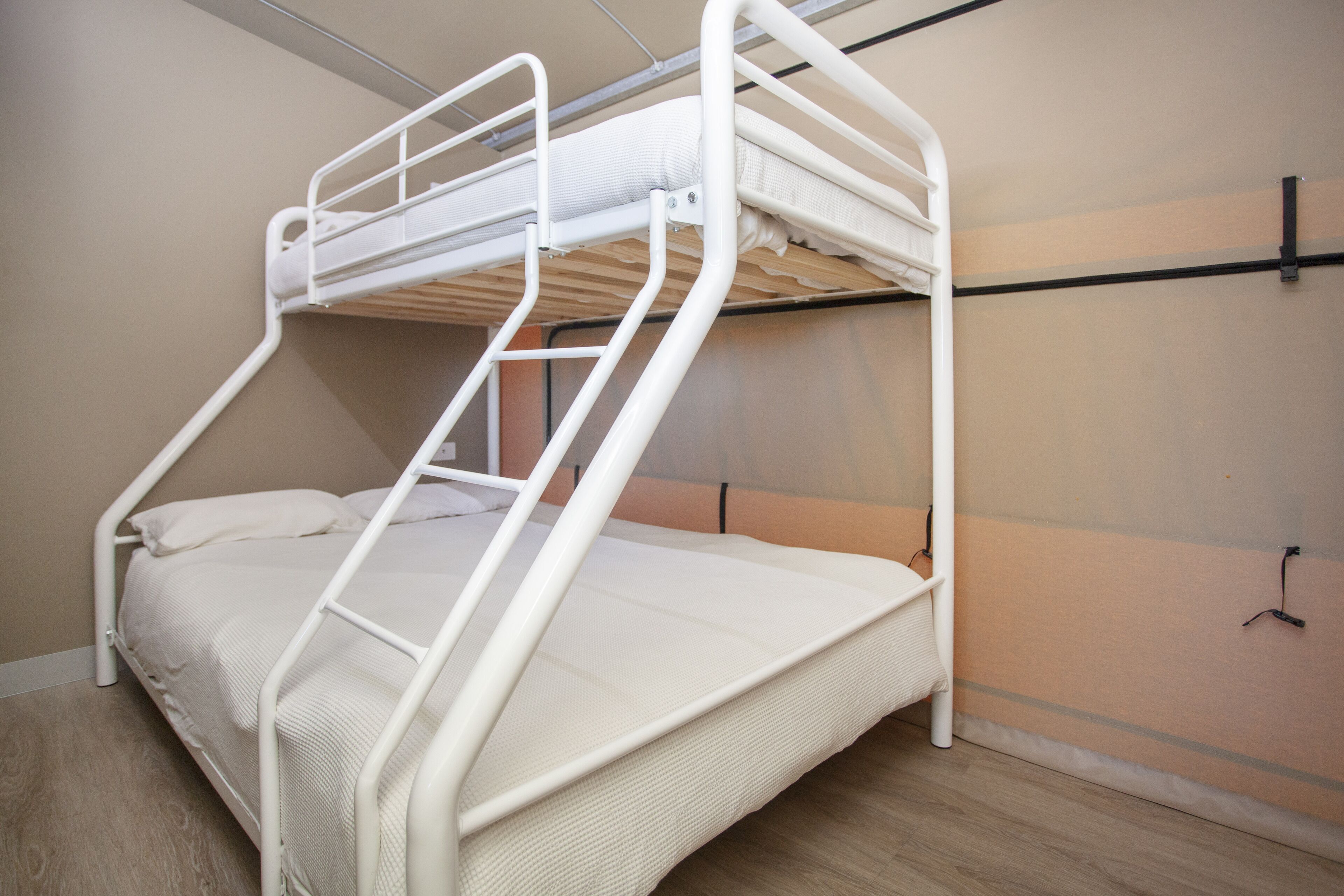 Una cama individual con estructura metálica blanca y un colchón.