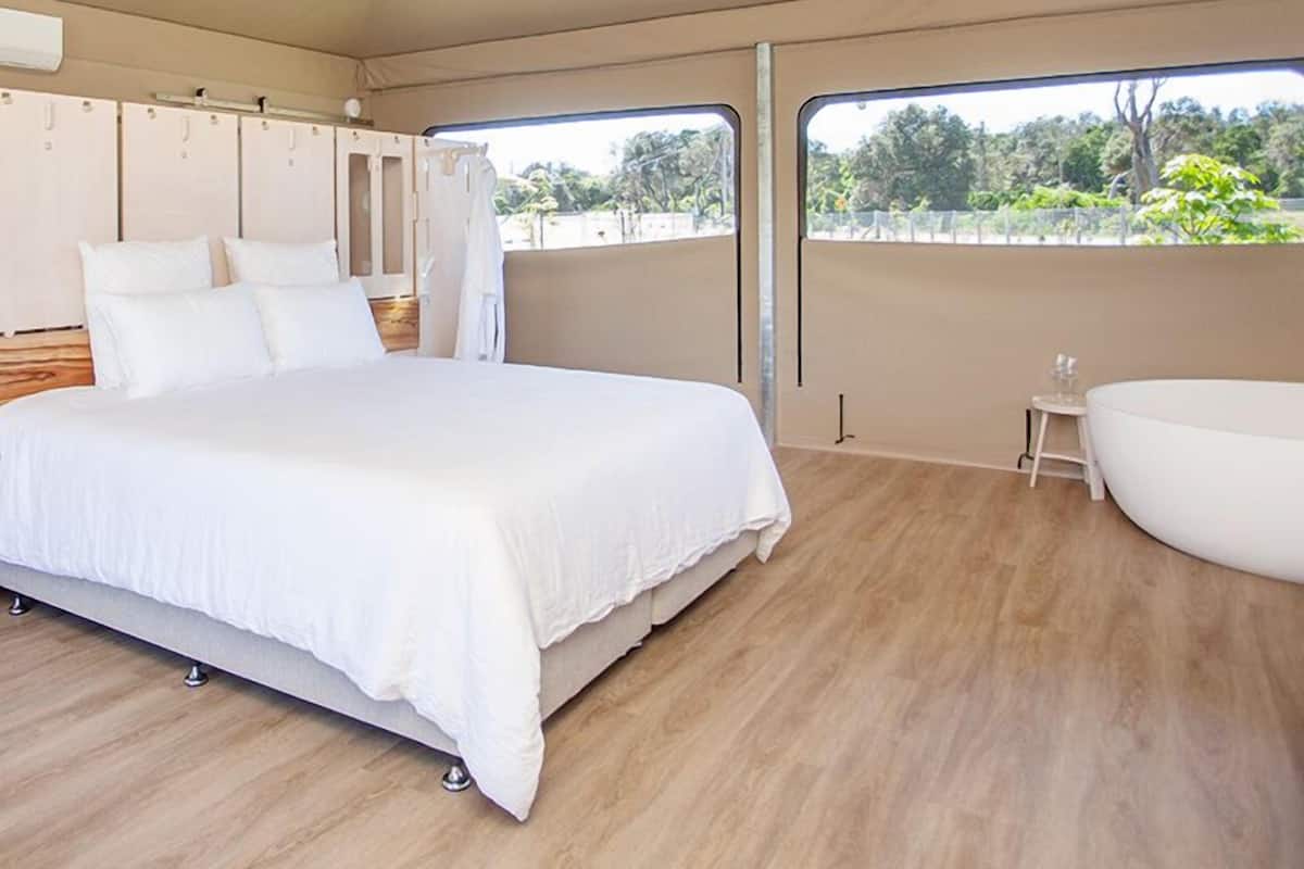 Ein Schlafzimmer mit einem Bett, einem Deckenventilator, einem Fenster und einer Badewanne.
