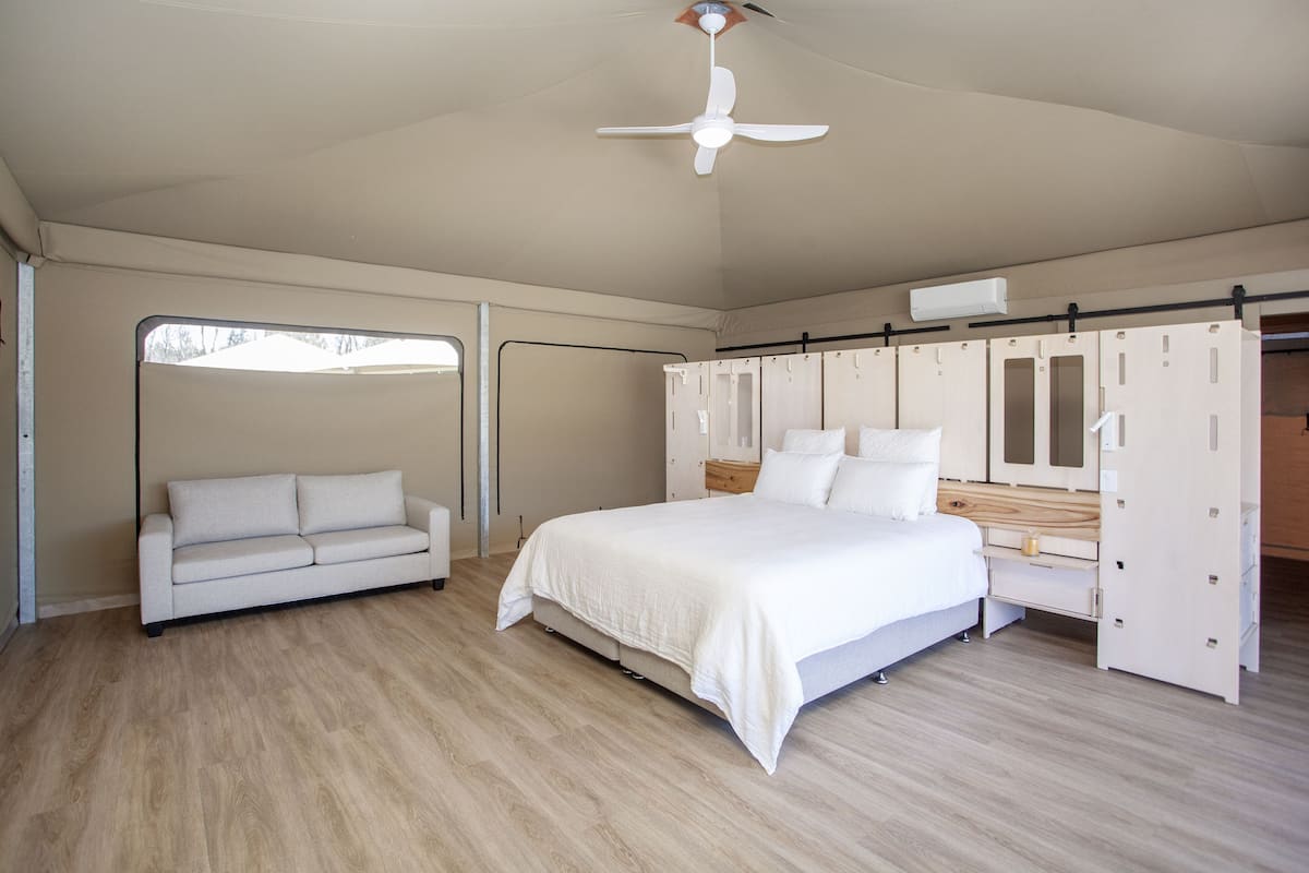 Ein Schlafzimmer mit einem Bett, einem weißen Sofa, einem Kleiderschrank und einem Deckenventilator.