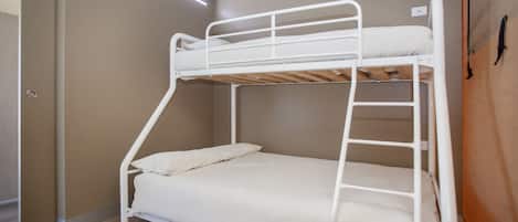 A bunk bed with a ladder, a door, and a light fixture.