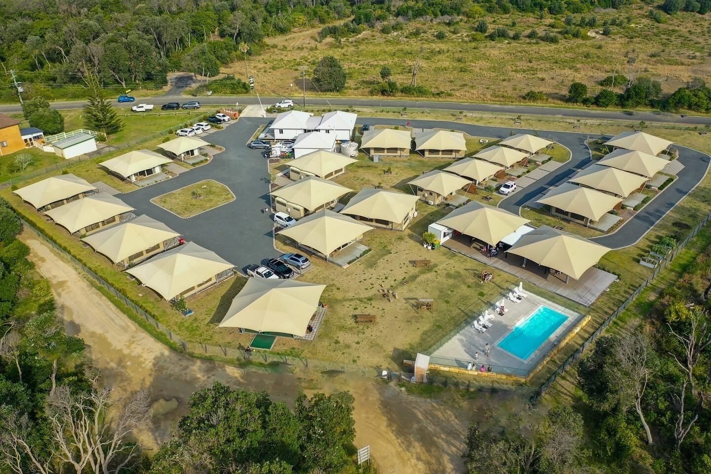 Vista aérea de un resort con varias tiendas en forma de cúpula, una piscina y un estacionamiento.
