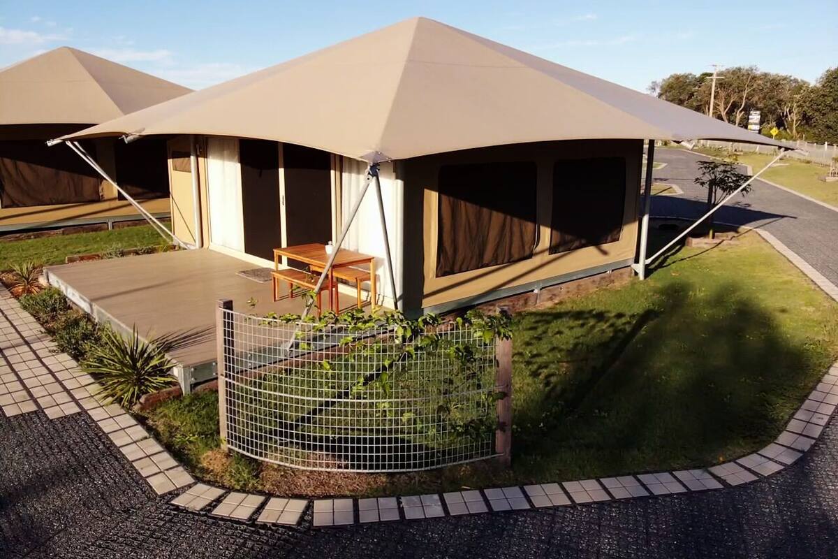 Eine caravanartige Unterkunft mit überdachter Außenbereich und umzäuntem Garten.