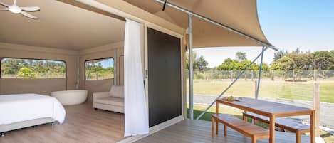 A spacious room with a bed, a sofa, a table, and a bench.