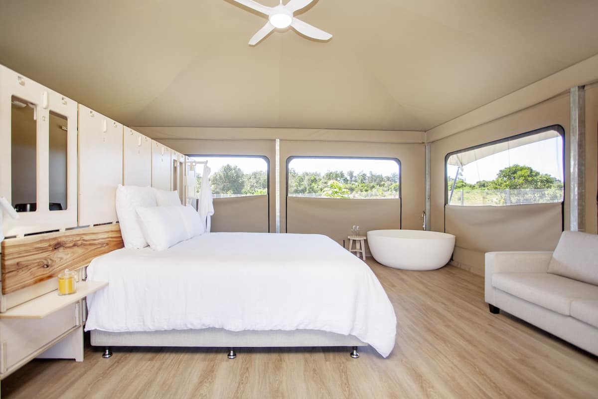 Ein modernes Schlafzimmer mit einem großen Bett, einer Badewanne, einem Sofa und einem Deckenventilator.