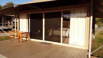A covered outdoor area with a wooden deck, a table, and a bench.