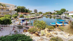A marina with boats docked, a swimming pool, and a building with a balcony. -  Charming Condo in Marco Island (Marco Island)