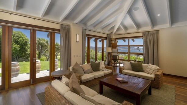 A spacious living room with a high ceiling, large windows, and a view of the outdoors.