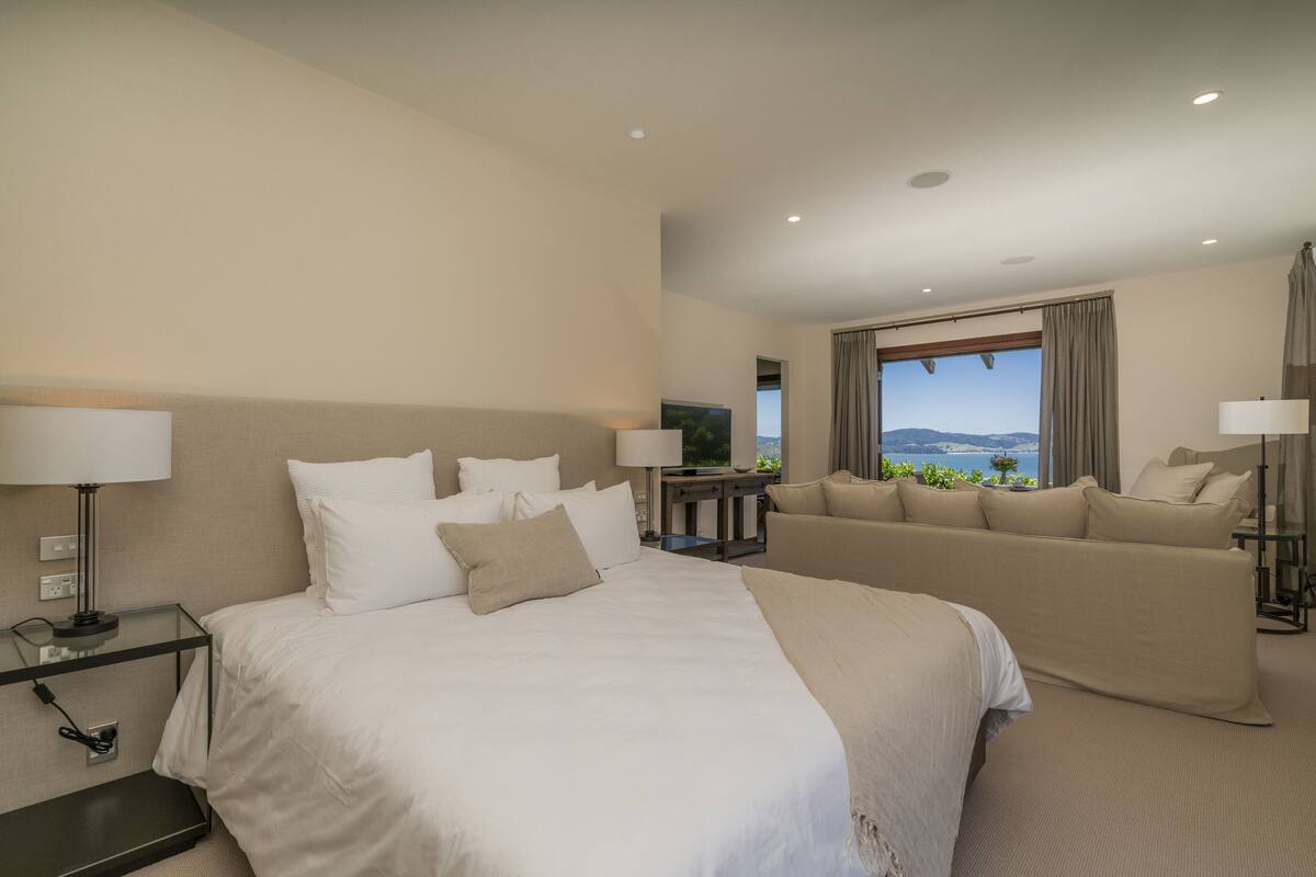 Ein Hotelzimmer mit einem großen Bett, einer Couch, einem Fernseher und Blick auf die Berge.