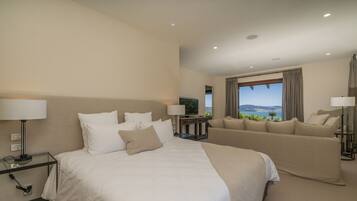 A hotel room with a large bed, a sofa, a TV, and a view of the mountains.