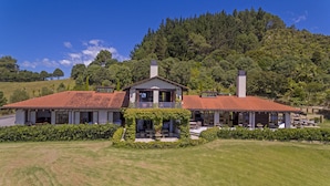 A two-story house with a red-tiled roof, a balcony, and a garden in front.
