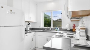 Une cuisine moderne avec des armoires blanches, une cuisinière encastrée et une fenêtre donnant sur l’extérieur.