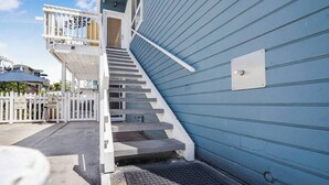 Un escalier menant à un balcon blanc doté d’une rambarde en métal.