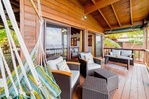 A wooden deck with wicker furniture, including sofas and a bench, and hammocks.