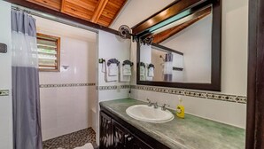 Ein Badezimmer mit großem Spiegel, Waschbecken und Duschbereich.