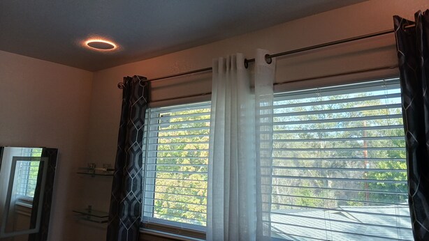 Ein Zimmer mit großem Fenster, Deckenventilator und integriertem Regal.