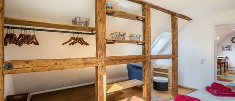Una habitación con una litera de madera, estantes de madera y una silla azul.