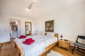 A bedroom with a bed, bedside table, chair, and a painting on the wall.
