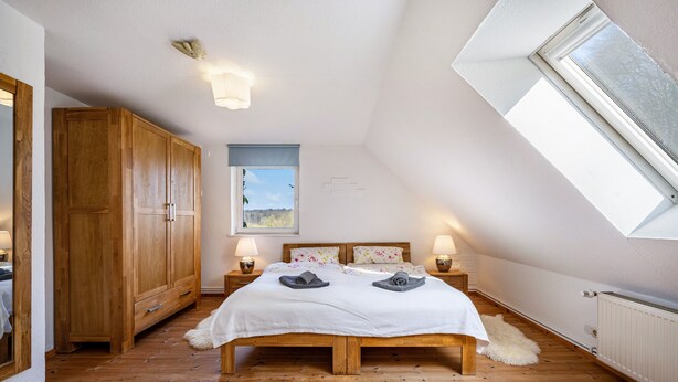 Un dormitorio con cama de madera, armario, tragaluz y vistas al exterior.