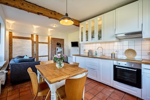 Een moderne keuken met witte kastjes, een houten eettafel en een ingebouwde oven.