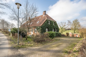Een huis met een bakstenen gevel, muur klimop en een geplaveid oprit.