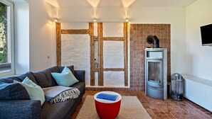 A modern living room with a sofa, a red ottoman, a fireplace, and a television. - Apartment "Voßberg Ferienwohnung 1" with Shared Terrace & Wi-Fi (Grömitz)