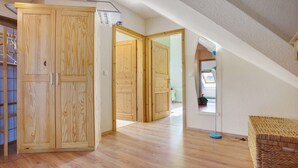 A room with wooden flooring, a wardrobe, a wicker bench, and a ceiling fan. - Apartment 'Ullo´s Schwalbennest  ' with Private Terrace, Shared Garden and Wi-Fi (Lütow)