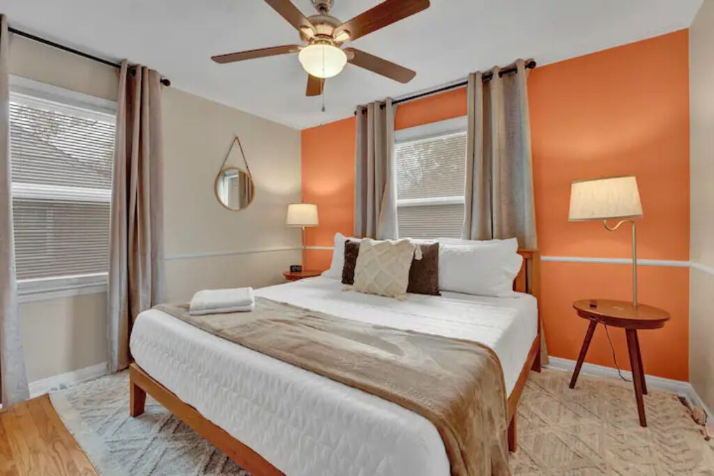 A hotel room with a bed, ceiling fan, two bedside lamps, and a small table.