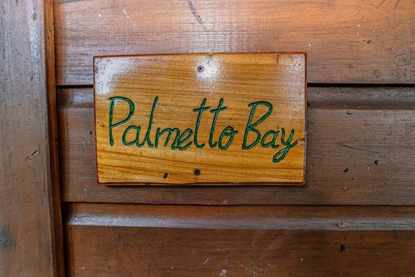 A wooden sign with the text "Palmetto Bay" on a wooden wall.