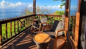 Una terraza de madera con mobiliario de mimbre y vista al océano.