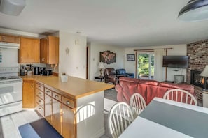 Une cuisine compacte avec des meubles en bois, un coin repas avec une table et des chaises, un canapé rouge et une cheminée.